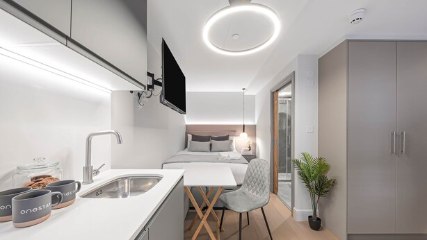 A modern kitchen with a built-in oven, a sink, and a flat-screen TV mounted above the counter.