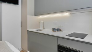 Eine moderne Küche mit Backofen, Spüle und einem flachbildfernseher darüber.