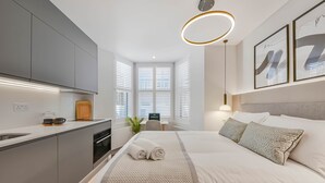 Ein modernes Hotelzimmer mit Bett, Schreibtisch und einer Küchenzeile.