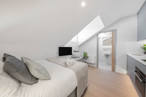 Une chambre moderne comprenant un lit, une télévision, une salle de bain et un coin cuisine.