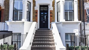 A multi-story building with a black front door, white trim, and a brick facade.