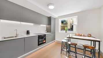 Een moderne keuken met grijze kastjes, een ingebouwde oven, een spoelbak en een raam met uitzicht op een tuin.