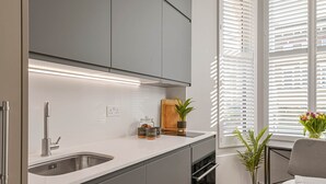 A modern kitchen with a stainless steel sink, a wooden cutting board, and a potted plant.