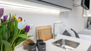 Une cuisine moderne avec un plan de travail blanc, un évier et un vase de tulipes.