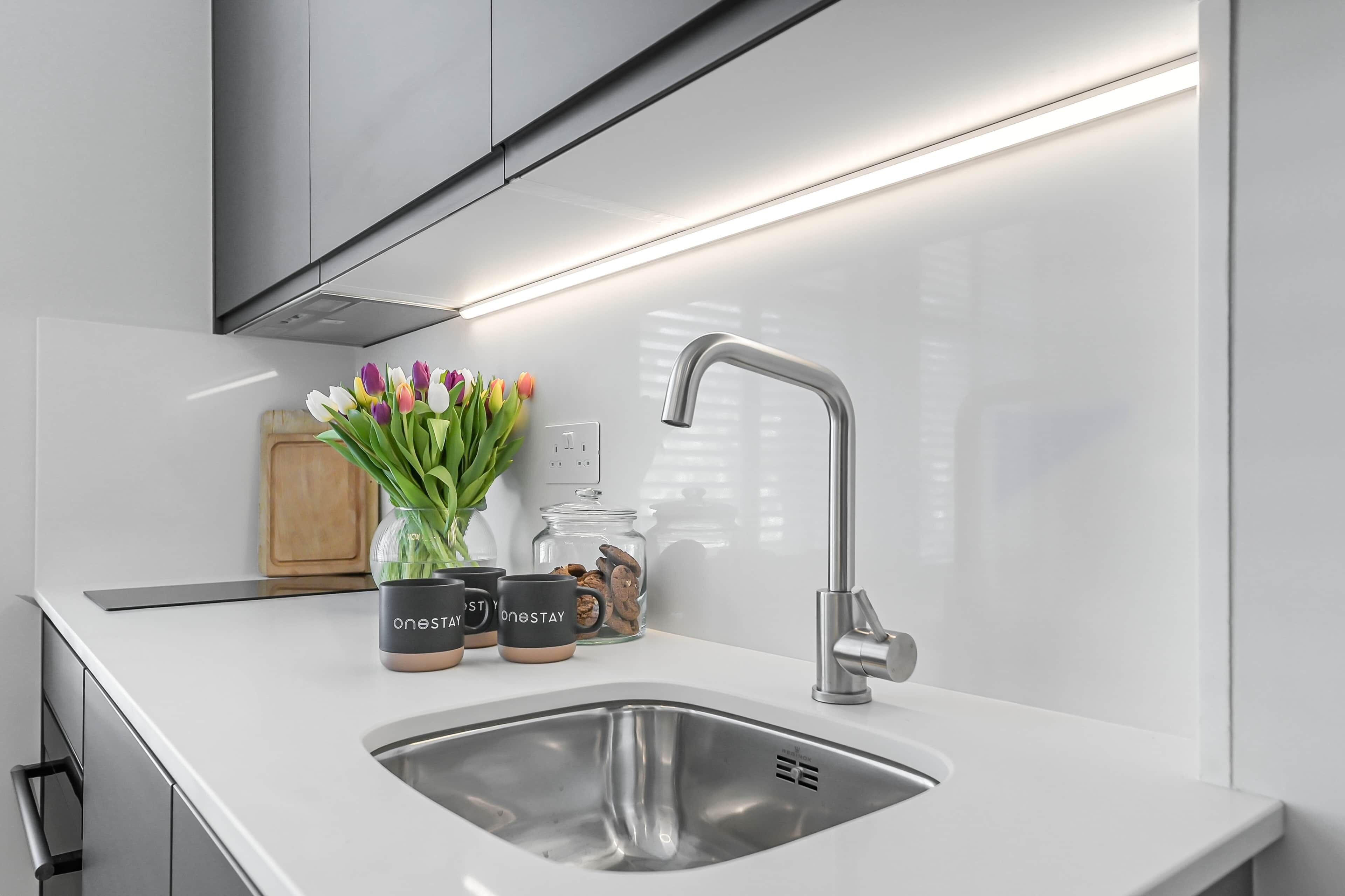 A modern kitchen with a stainless steel sink, a built-in oven, and a range hood.