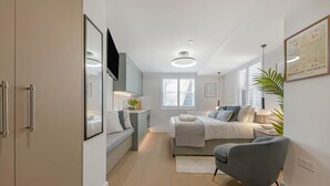 A modern bedroom with a bed, bedside table, lamp, and a large window. - Studio 5 @ OneStay Maida Vale (London)