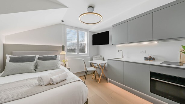 Un dormitorio moderno con cama, mesita de noche y un pequeño escritorio con silla.