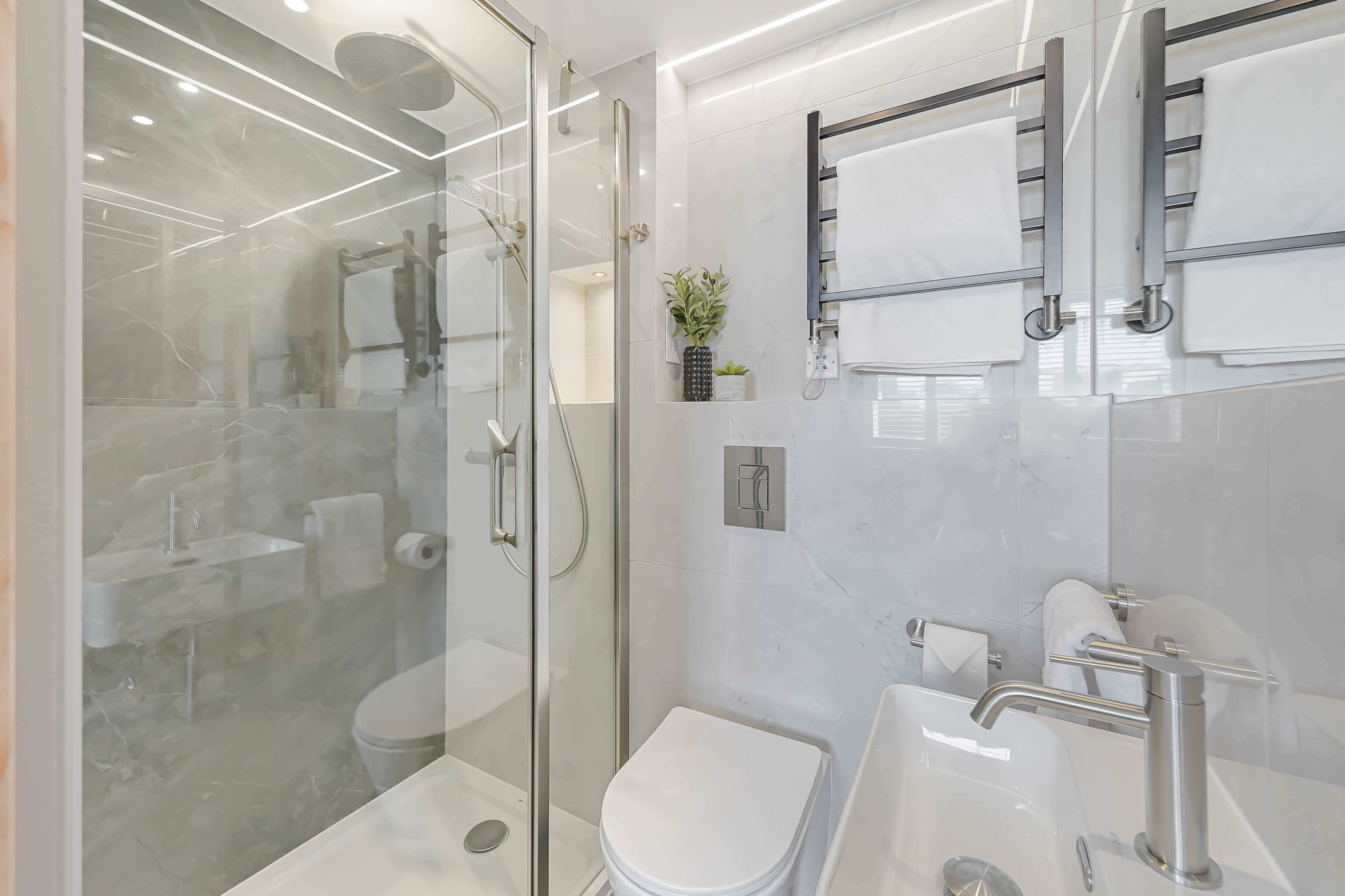 Une salle de bain moderne avec une douche à parois de verre, des toilettes et un lavabo avec un miroir au-dessus.