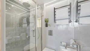 Un baño moderno con ducha de vidrio, inodoro y lavabo con espejo.