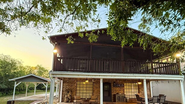 Un edificio de dos pisos con un patio cubierto, un letrero que dice "COME IN" y asientos al aire libre.