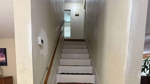 Una escalera con paredes blancas y escalones de madera que conducen a una plataforma.