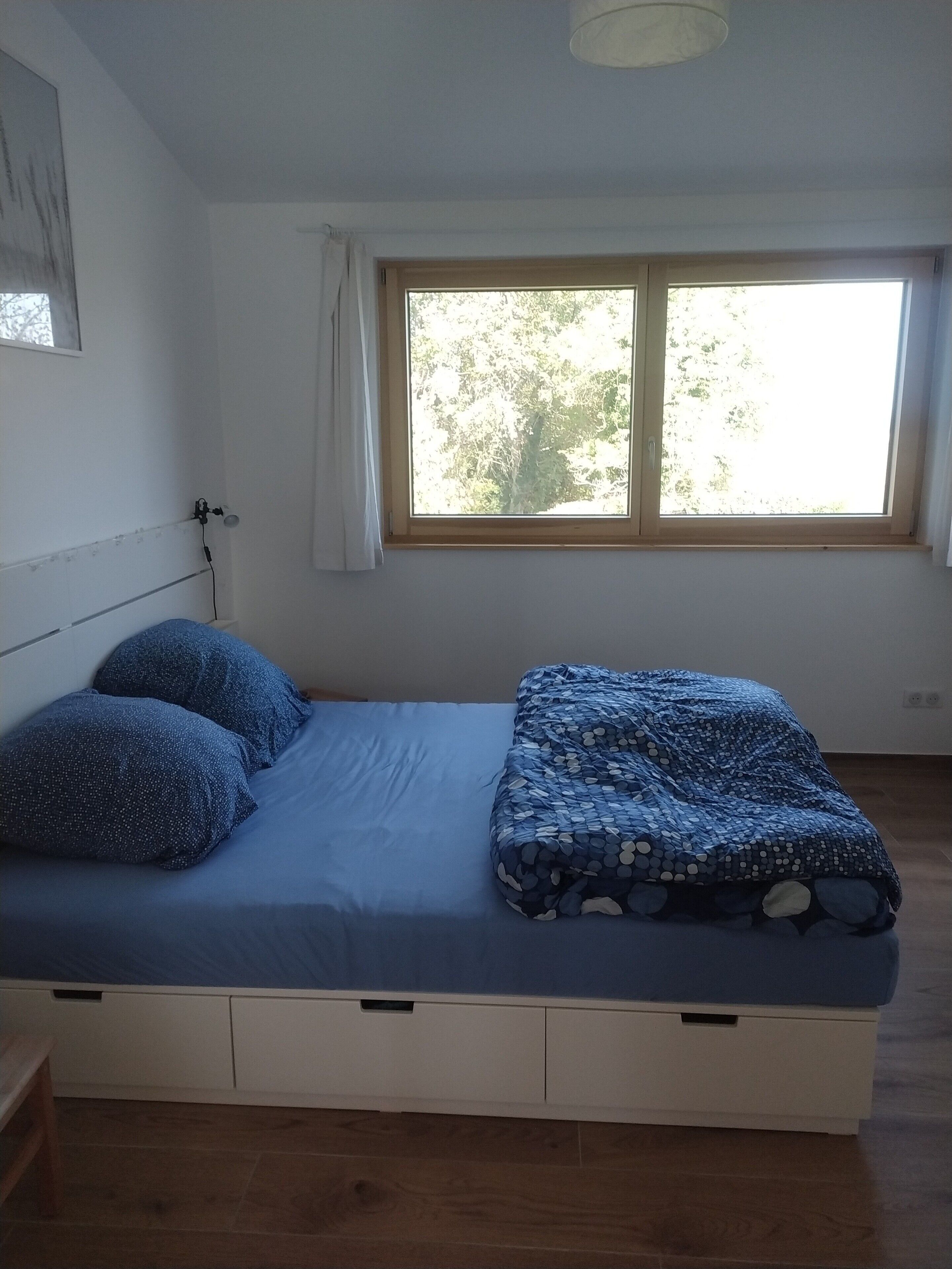 A bedroom with a bed, a window, and a ceiling light.