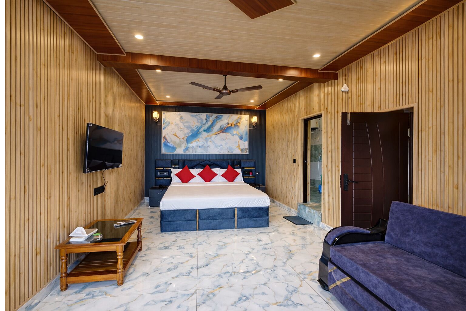 A bedroom with a bed, a TV, a ceiling fan, a marble floor, and a sofa.