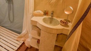 A compact, well-lit bathroom with a shower, a sink with a mirror, and a towel rack. - Les Pyramides Merzouga Camp (Merzouga)