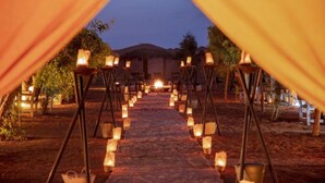 A pathway lined with lanterns leading to a building. - Les Pyramides Merzouga Camp (Merzouga)