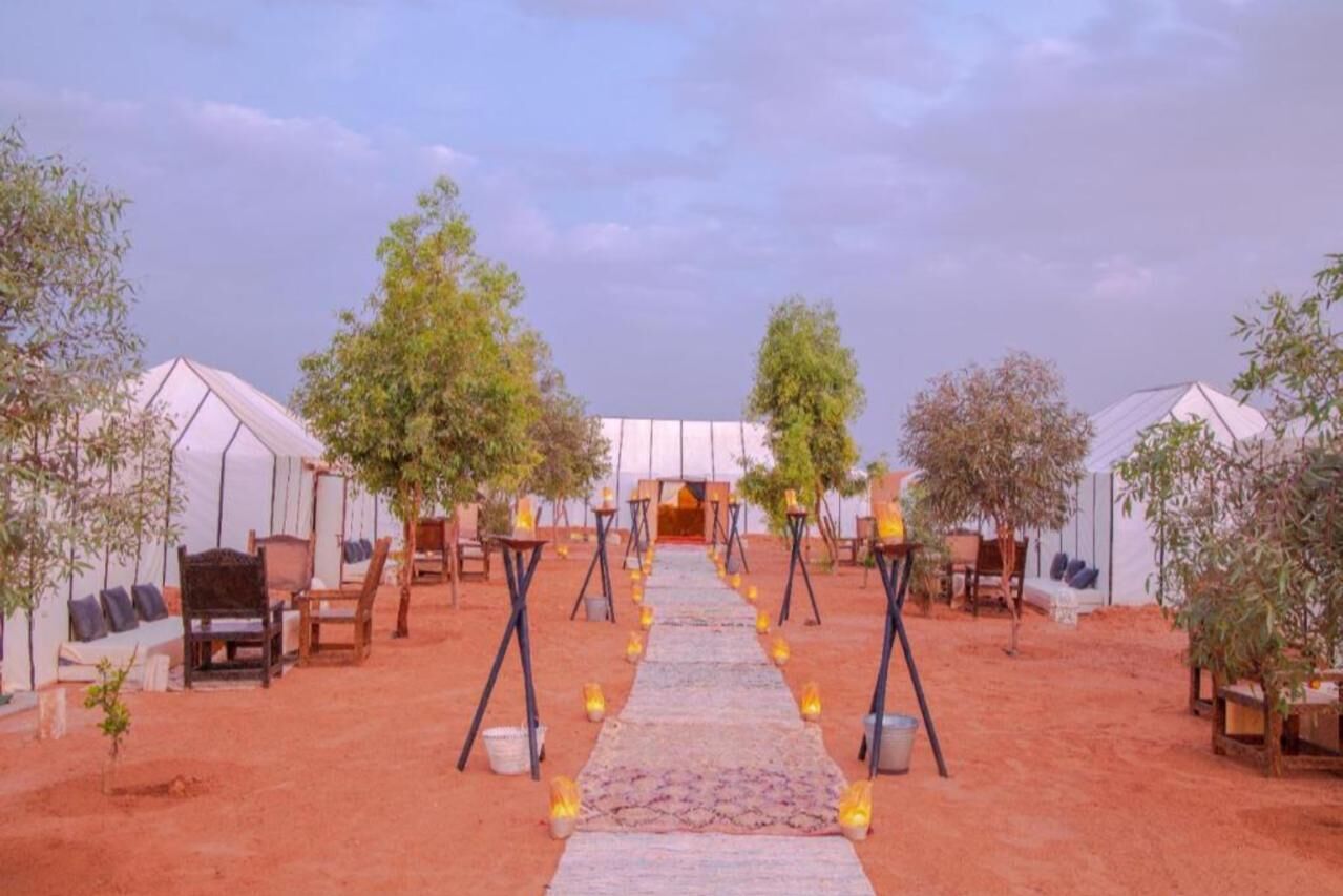A desert wedding venue with tents, a carpeted aisle, and seating arrangements.