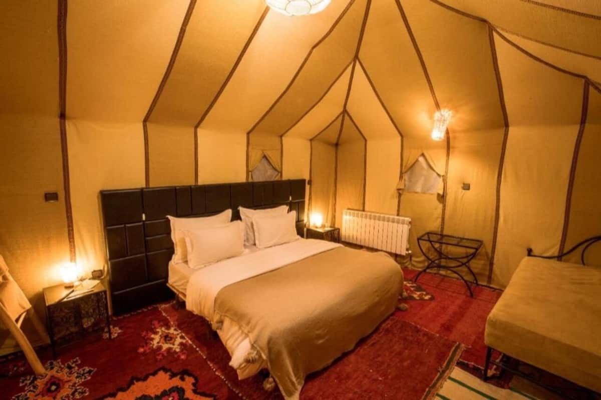 A tent-style room with a bed, a chair, and a small table.