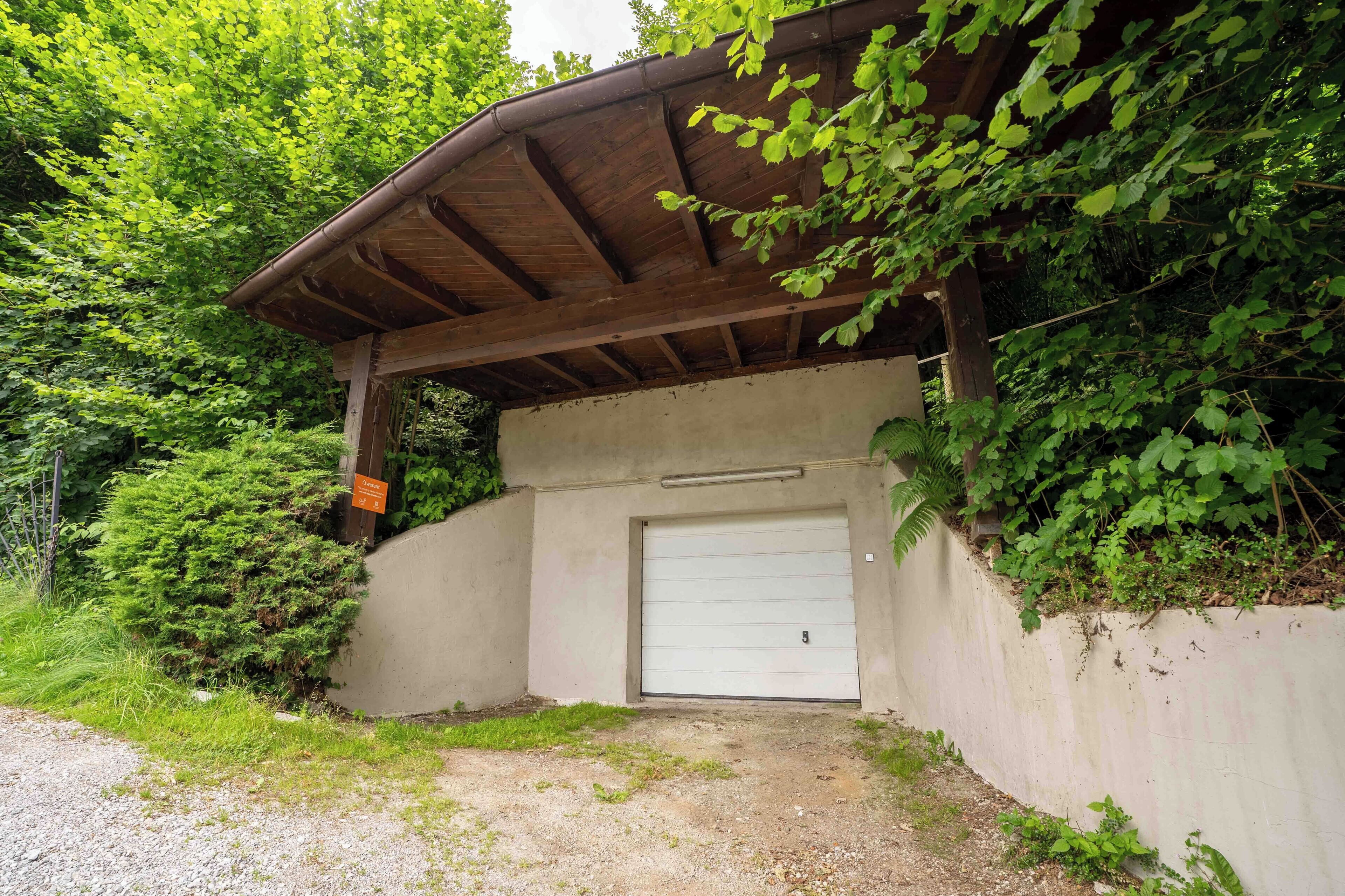 A covered entrance to a building with a concrete wall and a white garage door.