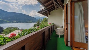 A balcony with a wooden railing, a chair, and a view of a lake and mountains. - Chalet Birkmayer by we rent (Zell am See)