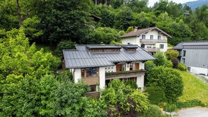 A multi-story house with a sloped roof, surrounded by lush greenery and trees. - Chalet Birkmayer by we rent (Zell am See)