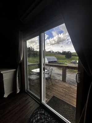 Una habitación con un amplio ventanal corredera que da a una terraza exterior con mesa y sillas.