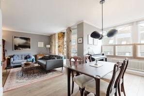 A modern living room with a sofa, a dining table, and a piano.