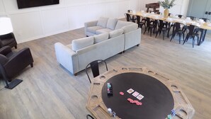 A modern living room with a sectional sofa, a dining area with a round table, and a flat-screen TV mounted on the wall. - Secluded Modern Farmhouse on 3 Acres - 4m. from all things Chickasha (Ninnekah)