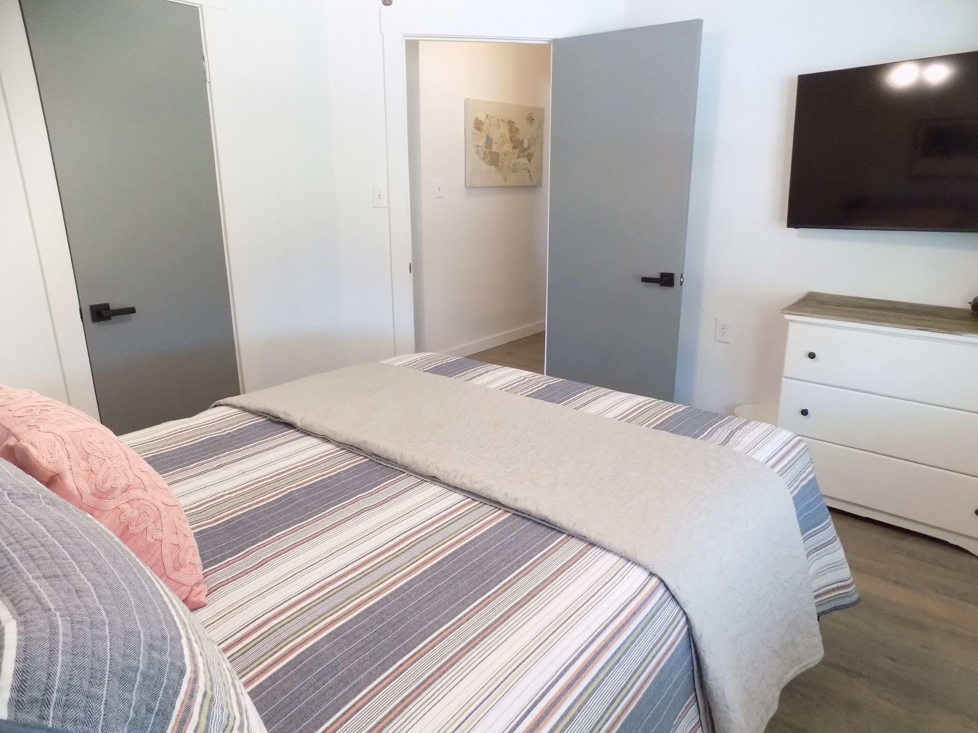 A bedroom with a bed, a dresser, and a TV on the wall.