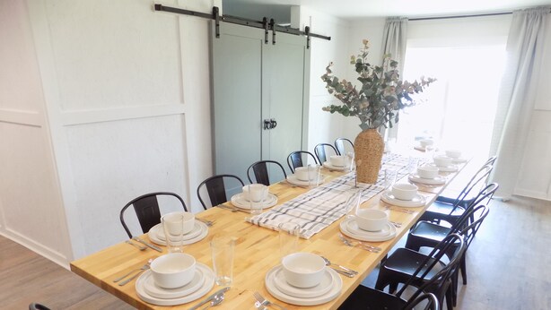 A dining room with a long wooden table set for a meal, surrounded by black chairs. - Secluded Modern Farmhouse on 3 Acres - 4m. from all things Chickasha (Ninnekah)