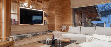 Una sala de estar acogedora con detalles de madera, un televisor de pantalla plana grande, un sofá, una mesa de centro y una estantería.
