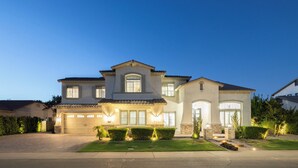 A two-story house with a garage, large windows, and a well-maintained lawn. - Luxury Outdoor Living - Heated Pool and Hot Tub (Chandler)