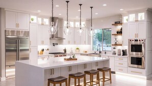 A modern kitchen with white cabinetry, stainless steel appliances, and a central island with stools. - Luxury Outdoor Living - Heated Pool and Hot Tub (Chandler)