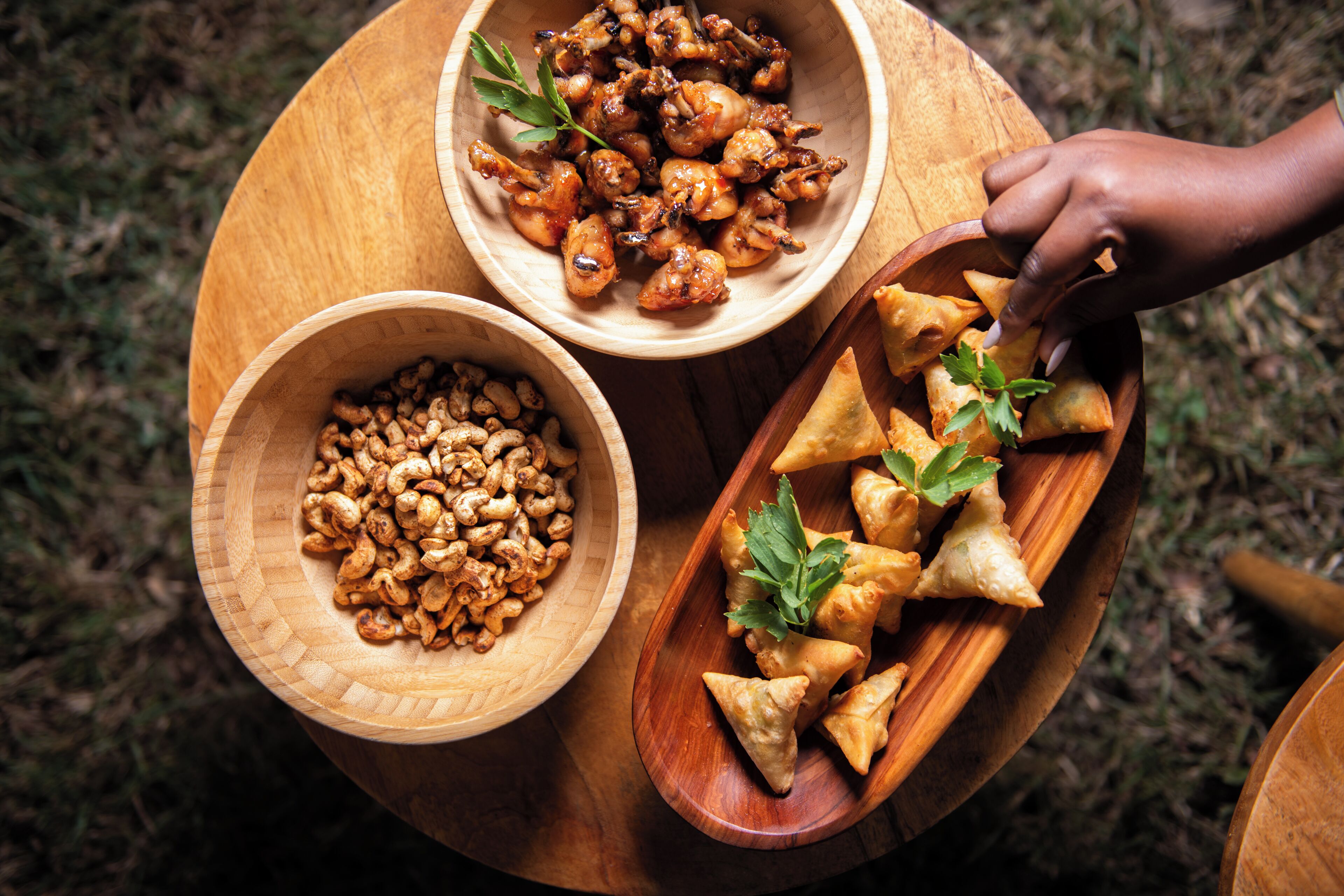 A wooden table with three bowls containing snacks.