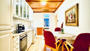 Une cuisine avec des meubles en bois, une cuisinière et un coin repas comprenant des chaises et une table.