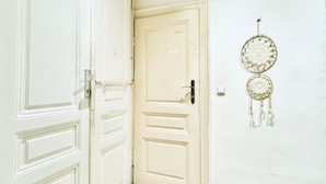 Une porte blanche avec une serrure et un attrape-rêves accroché au mur.