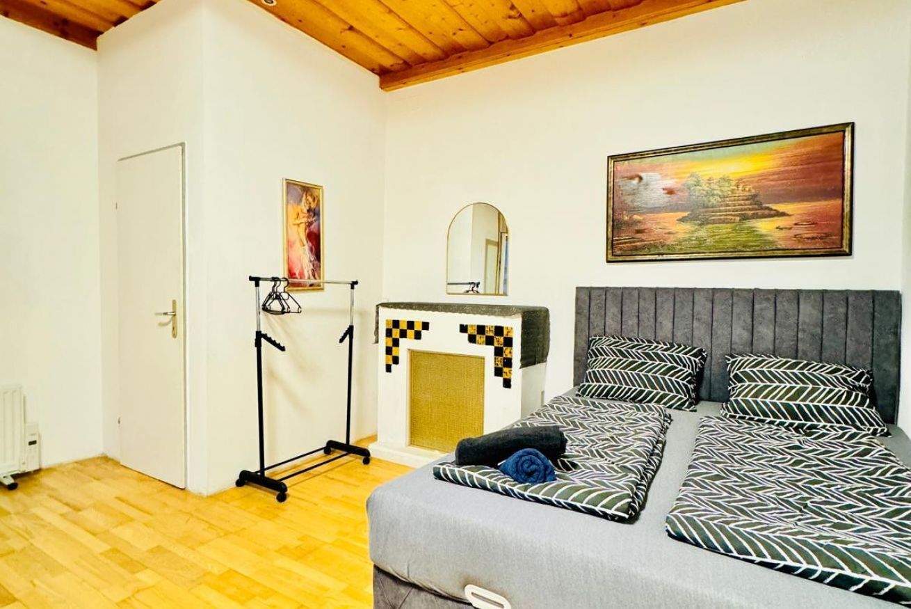 Ein Schlafzimmer mit einem Bett, einem Spiegel, einem Gemälde und einer Heizung.