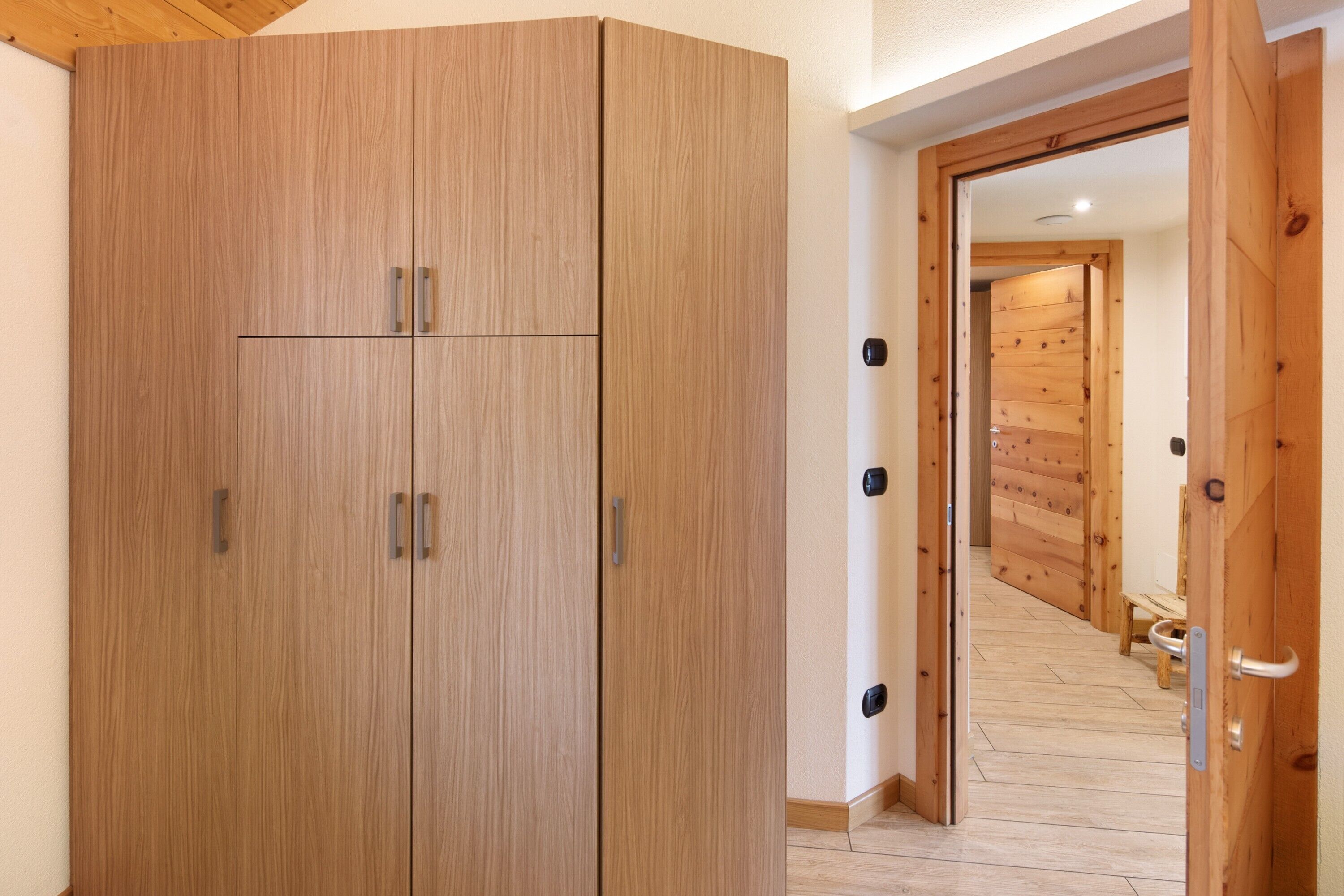 Un armario de madera con dos puertas y un tirador, una puerta de madera con un tirador, y un suelo de madera.