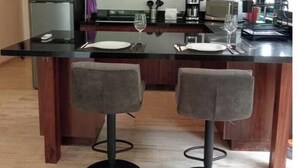 A modern kitchen with a central island, two bar stools, a refrigerator, and a coffee maker. - Practical and Comfortable Loft (Tulum)