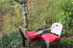 A wooden bench with red cushions in a garden setting.