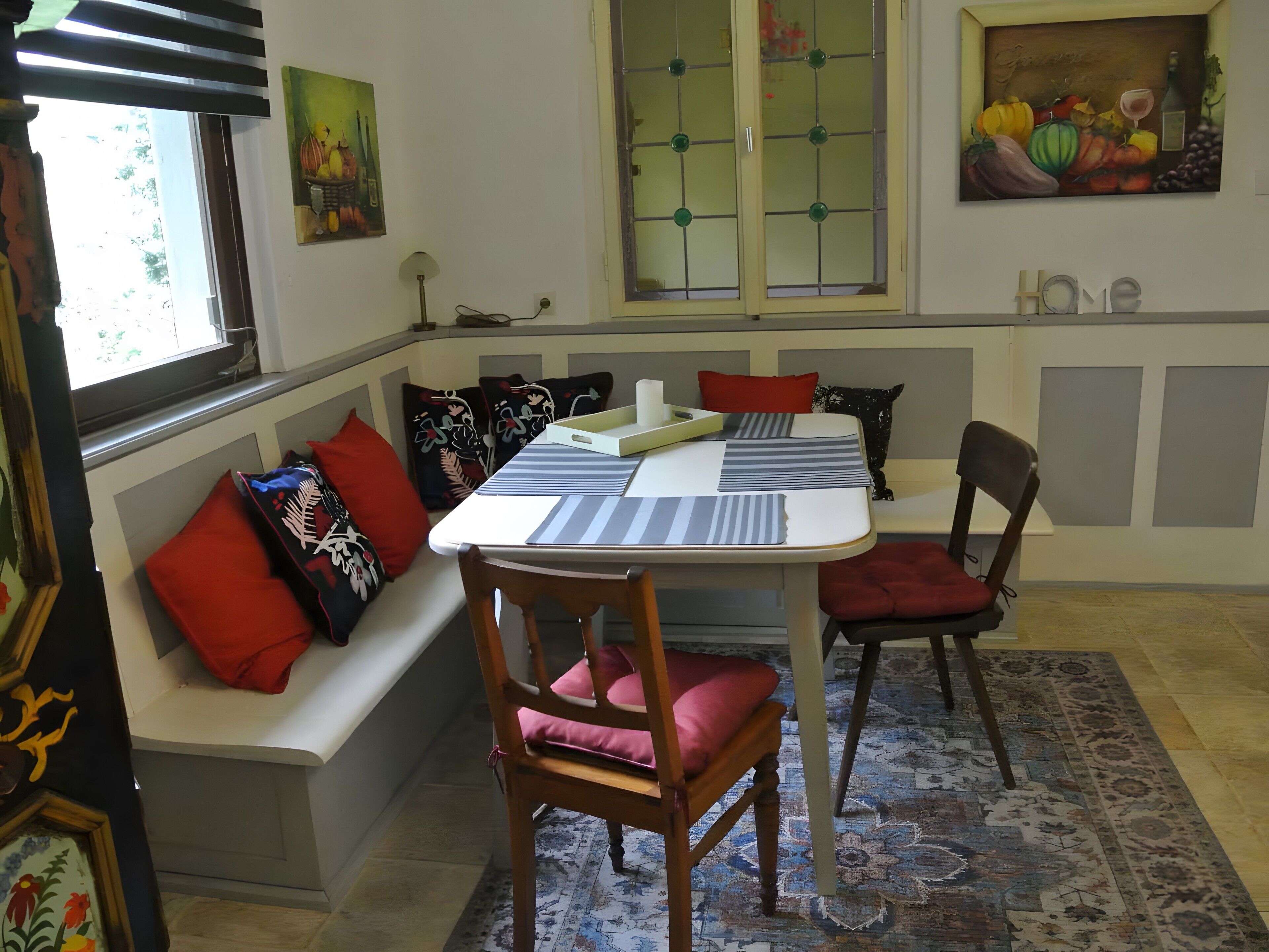 A dining area with a table, chairs, a bench, and a window.