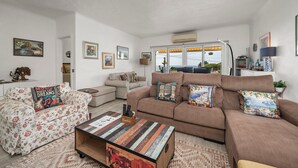 A living room with a sofa, armchairs, a coffee table, and a view through a large window. - Apartment 'Gudrun' with Sea View, Wi-Fi and Air Conditioning (Praia do Carvoeiro)