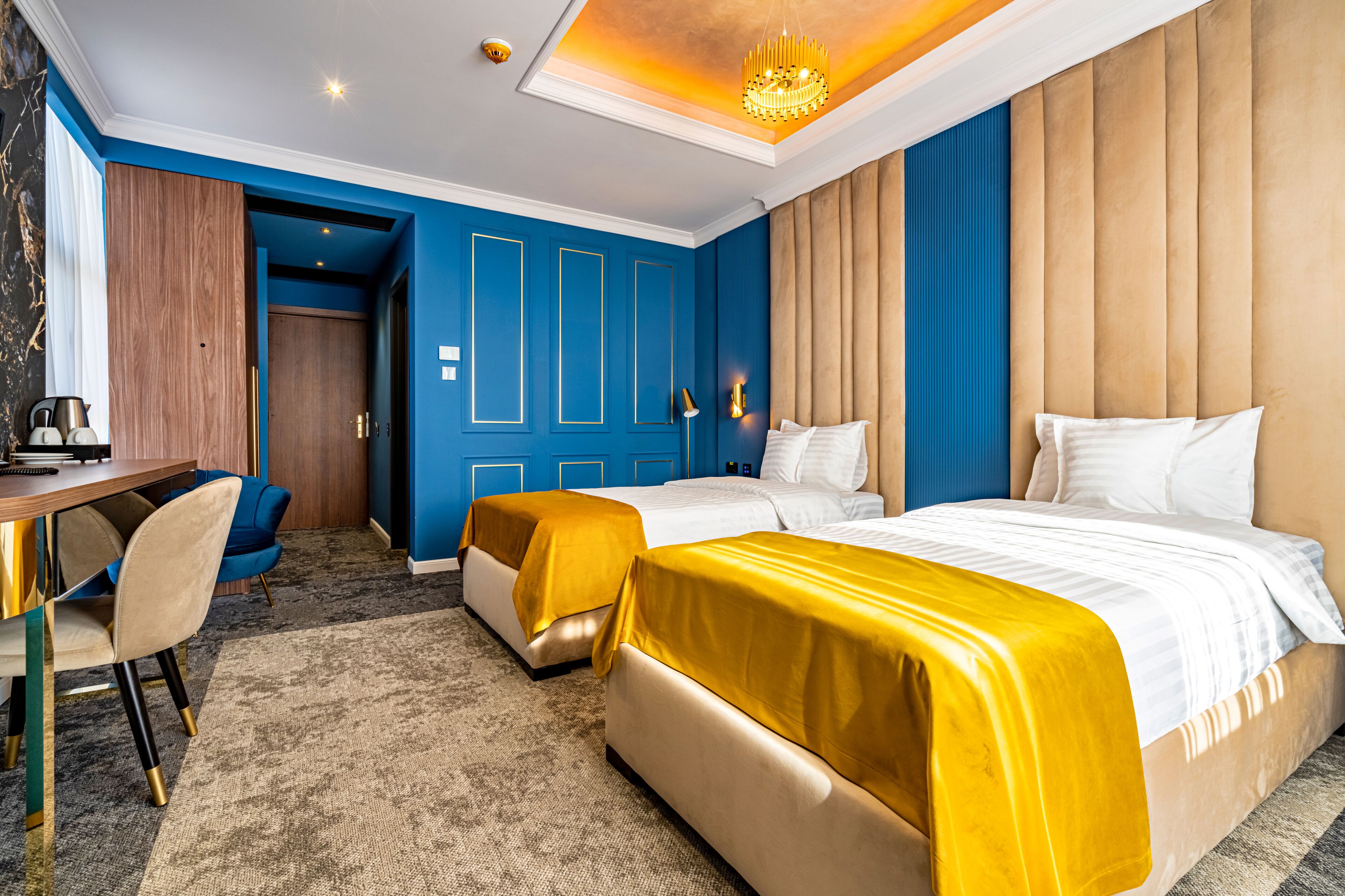 A hotel room with two beds, a desk, and a chair.