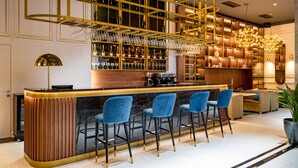 A modern bar area with a curved counter, blue bar stools, and a wine rack. - PRESTIGE PLAZA (Suceava)