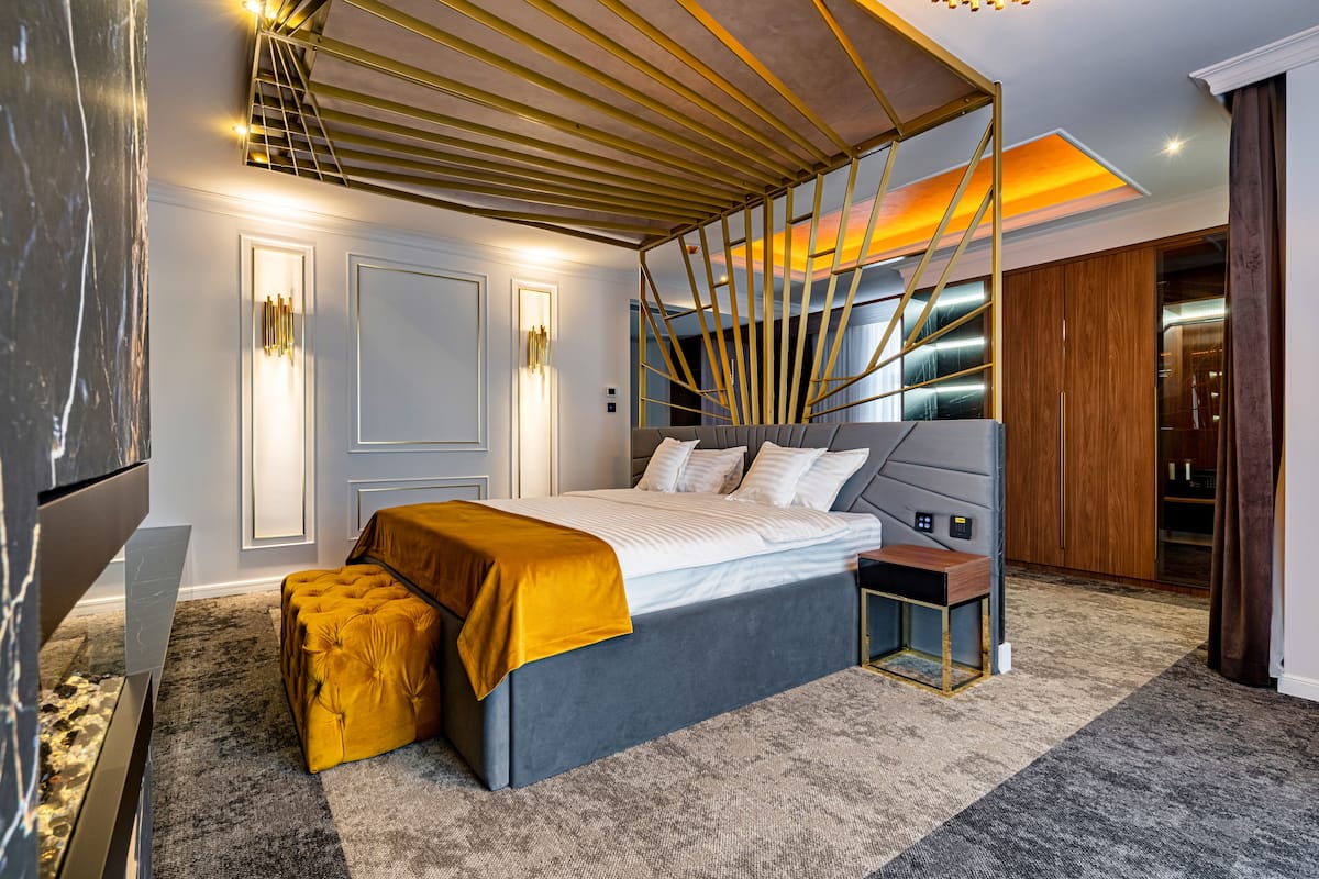 A modern bedroom with a large bed, a bedside table, a bench, and a wardrobe.