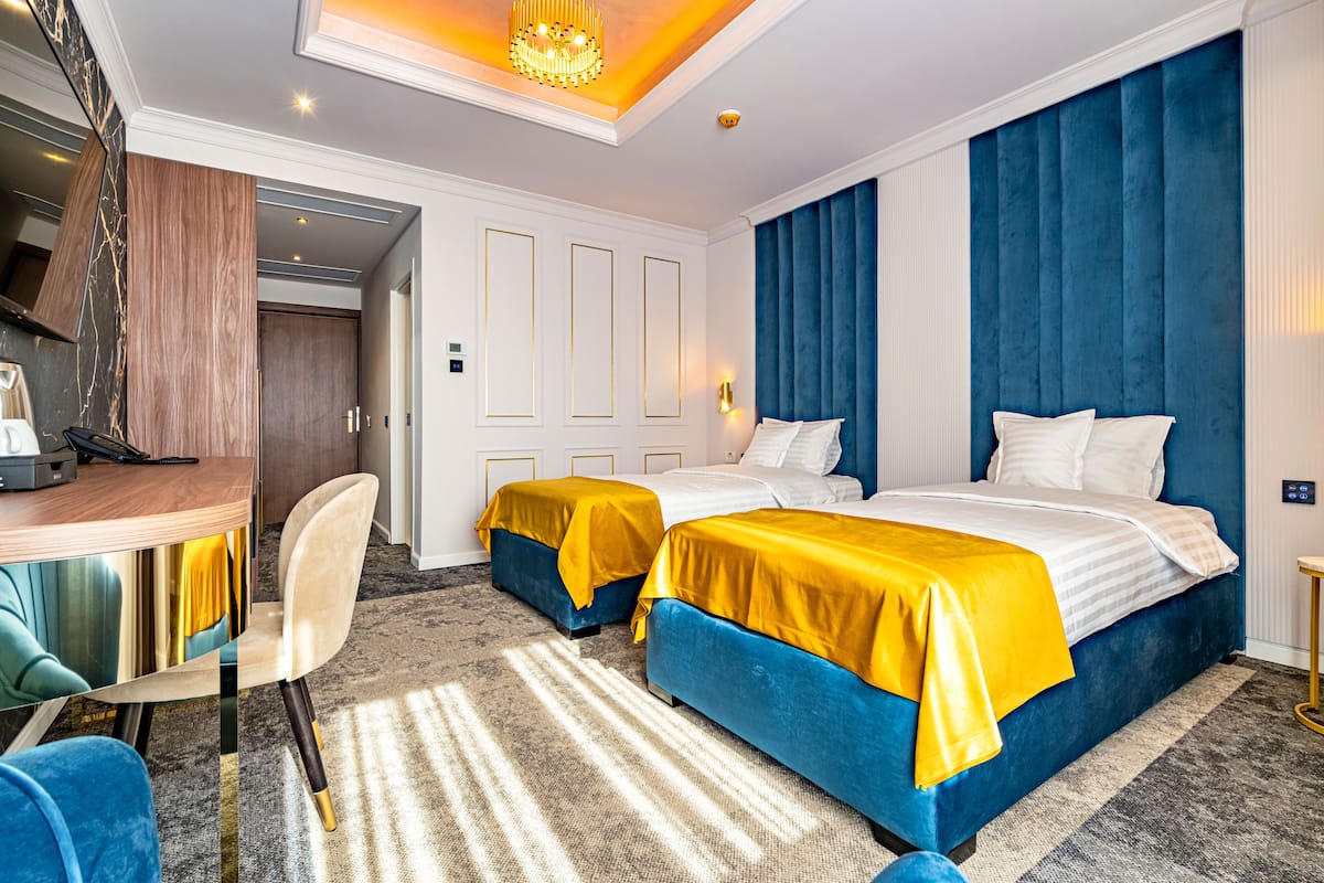 A hotel room with two beds, a desk, and a chair.