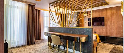 Habitación de hotel moderna con barra de mármol, zona de estar confortable y televisor grande.