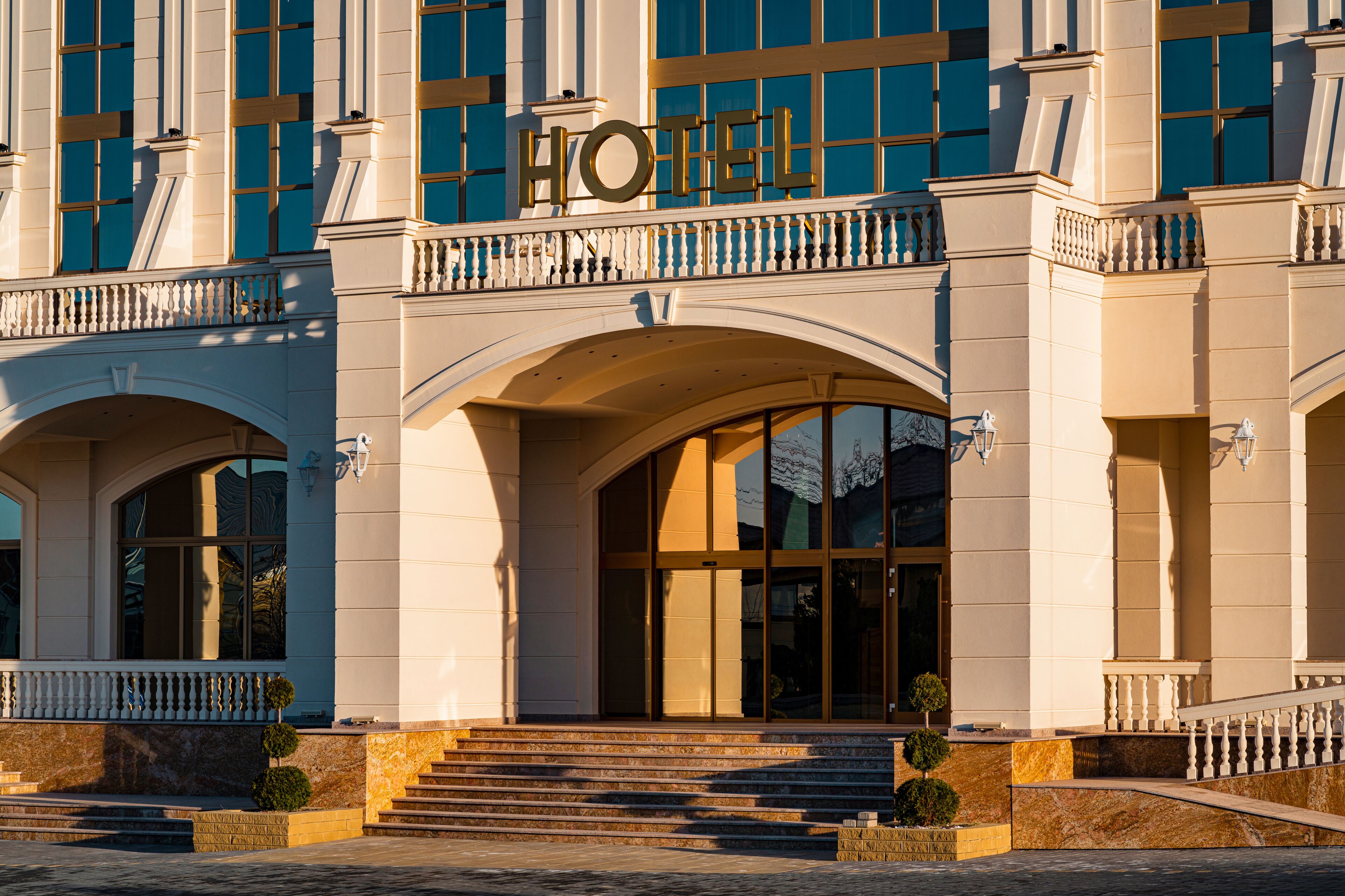 A hotel entrance with a grand archway, large windows, and a sign above the entrance.