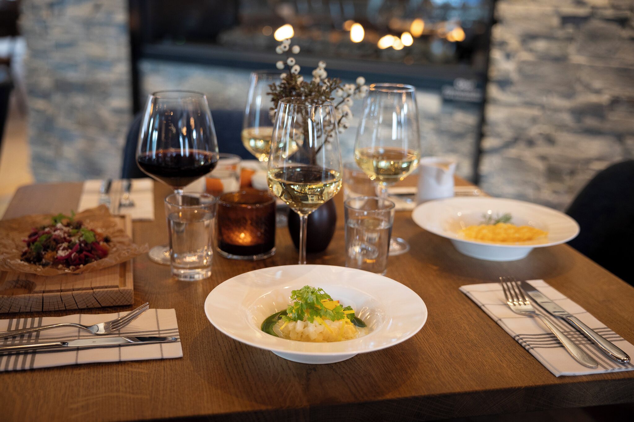 Une table à manger dressée avec des assiettes remplies de nourriture, des verres à vin et des couverts.