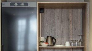 A compact kitchen with a black refrigerator, wooden cabinets, and a countertop with a kettle, coffee maker, and glassware. - Skistar Lodge Hundfjället  (Lima)