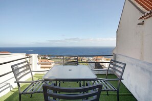 A balcony with a table and chairs, overlooking a coastal view. - Villa 'Seaside Haven - Soulful Stays' with Sea View, Wi-Fi and Air Conditioning (Porto Moniz)